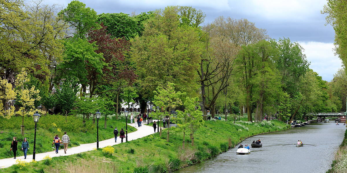 Link naar foto in Flickr: de groene Catharijnesingel met links lopende mensen en boten in het water