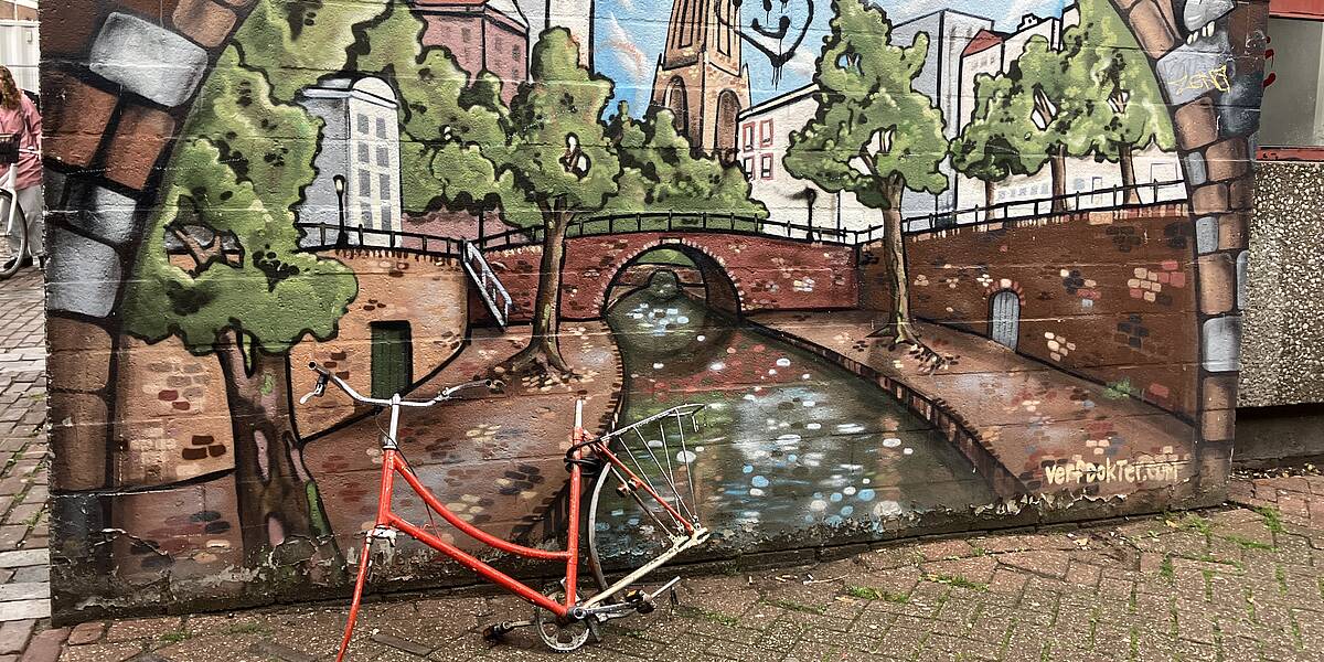 Link naar foto in Flickr: een kapotte fiets staat voor een muurschildering van de Oudegracht.