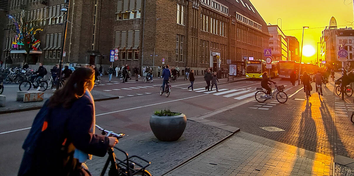 Link naar foto in Flickr: zonsondergang in de binnenstad. Fietsers, wandelaars en bussen ter hoogte van De Neude.