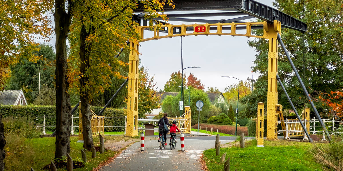 Link naar foto in Flickr: moeder en kind fietsen over de Jeremiebrug in het Maximapark.