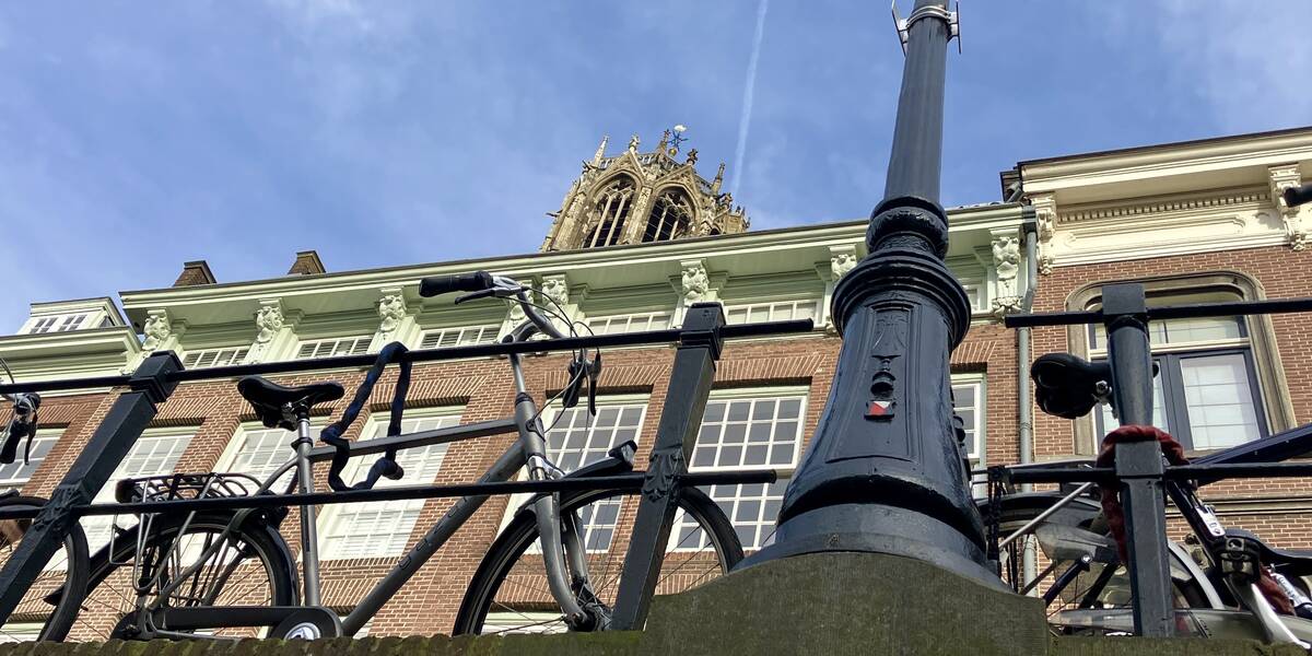 Link naar foto in Flickr: een fiets staat tegen de grachtrails naast een Lantarenpaal. Van onder de gracht bezien. Bovenaan nog een puntje van de Dom zichtbaar. 