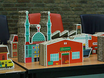 kartonnen gebouwen uit het spel: kringloopwinkel, moskee, fabriek, station, flatgebouw, hijskraan