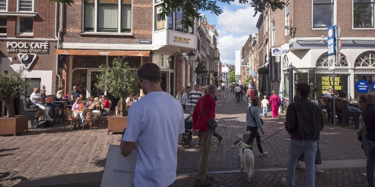Link naar foto in Flickr: winkelende mensen gaan over de Ganzenmarkt daarachter mensen op het terras in de zon.