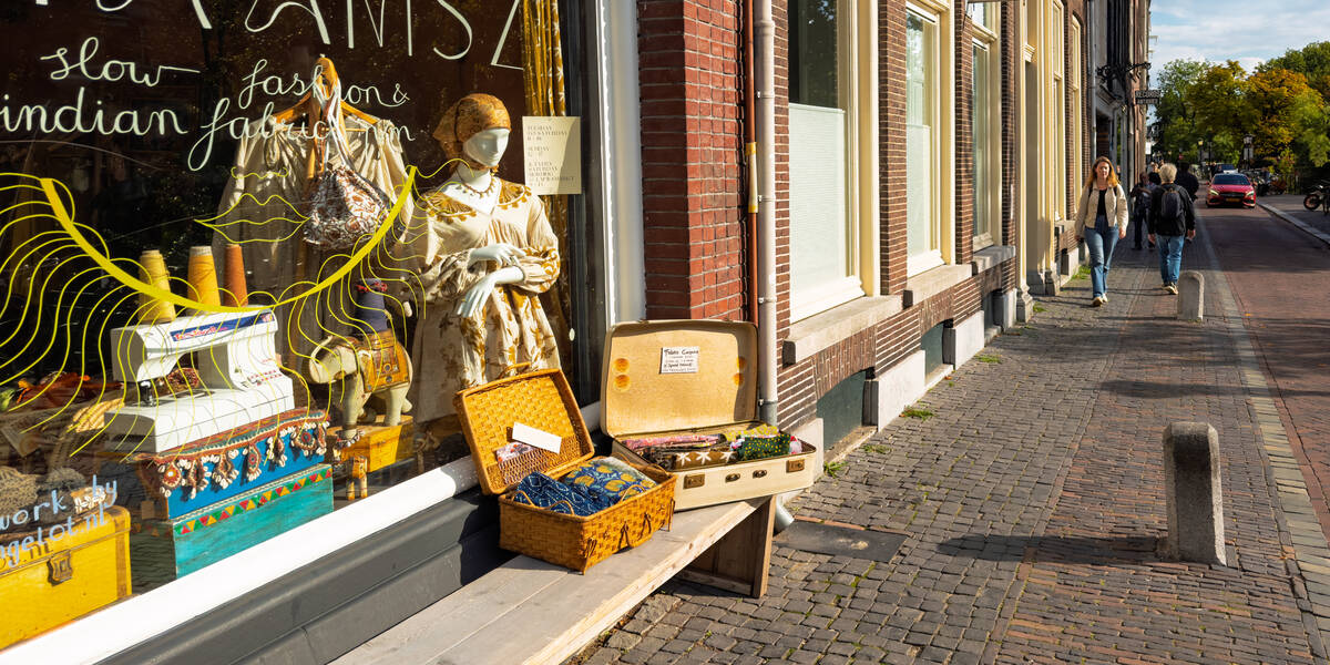 Link naar foto in Flickr: etalage van winkeltje aan de oudegracht en 2 mensen die aan komen lopen over de gracht.