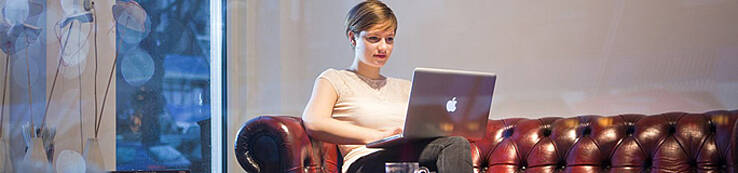Vrouw zittend op bank met laptop