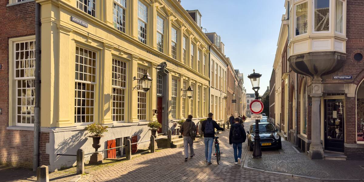Link naar foto in Flickr: drie mensen lopen in de zon door de straat. 