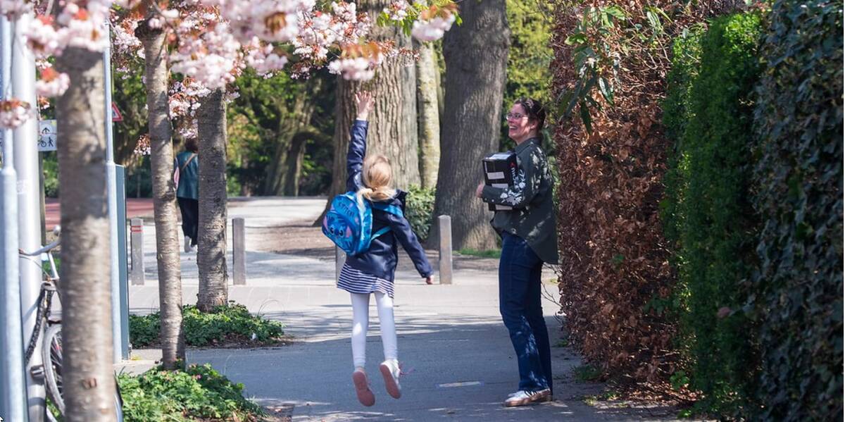 Link naar foto in Flickr: een meisje en een vrouw lopen onder de bloesembomen in de Everard Meijsterlaan.