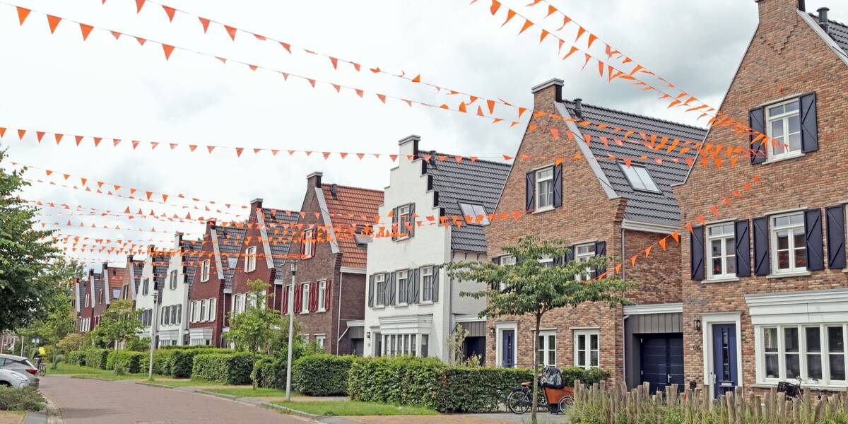 Mensen hangen oranje vlaggetjes op tussen de huizen in de nieuwe wijk Haarzicht.