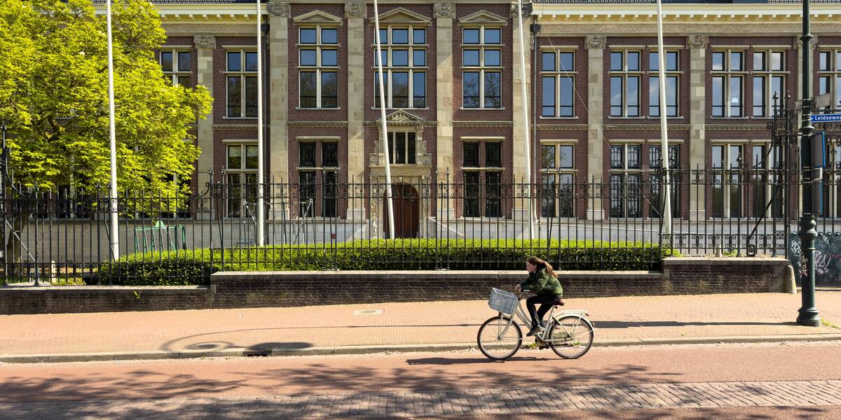 Link naar foto in Flickr: meisje fietst voor het Muntgebouw aan de Leidseweg.