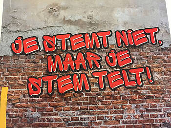 muur met tekst in graffitiletters: je stemt niet, maar je stem telt!