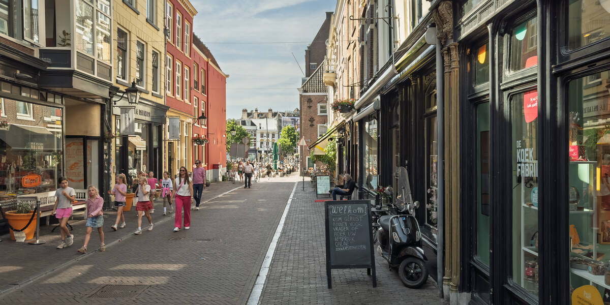 Link naar foto in Flickr: mensen lopen door een zonnige Schoutenstraat, op de achtergrond de Neude. 