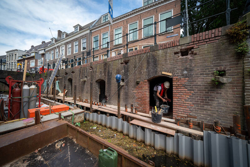 Een aannemer werkt aan de kluismuur en -kelders aan de Kromme Nieuwegracht. 