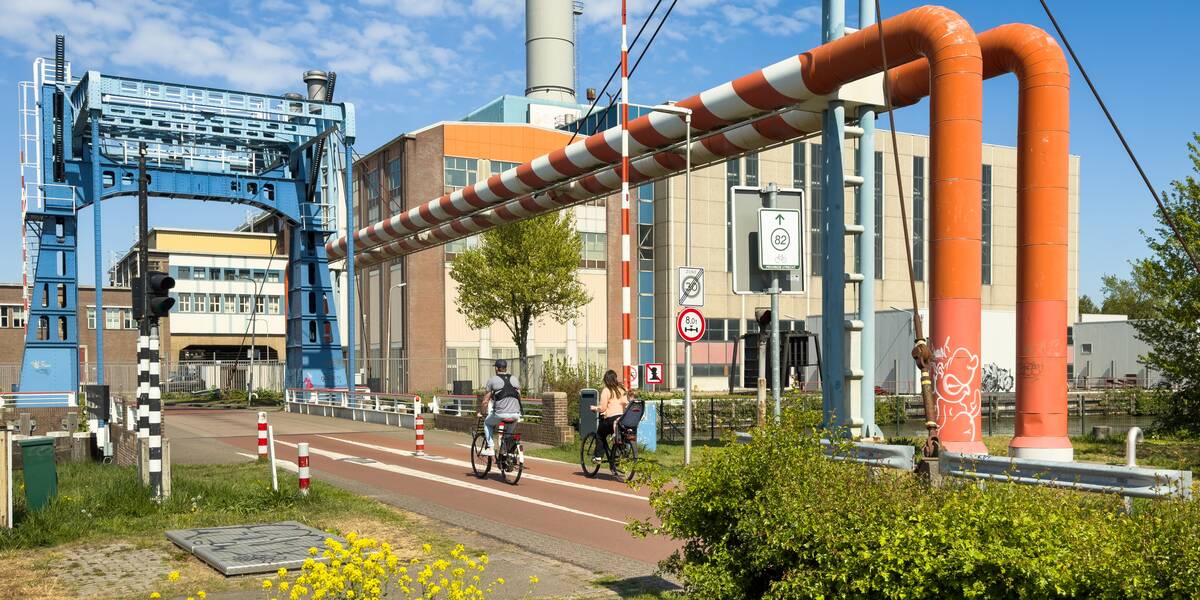 Link naar foto in Flickr: Industriehavenbrug met de Electriciteitscentrale Merwedekanaal. Twee fietsers gaan over de brug.
