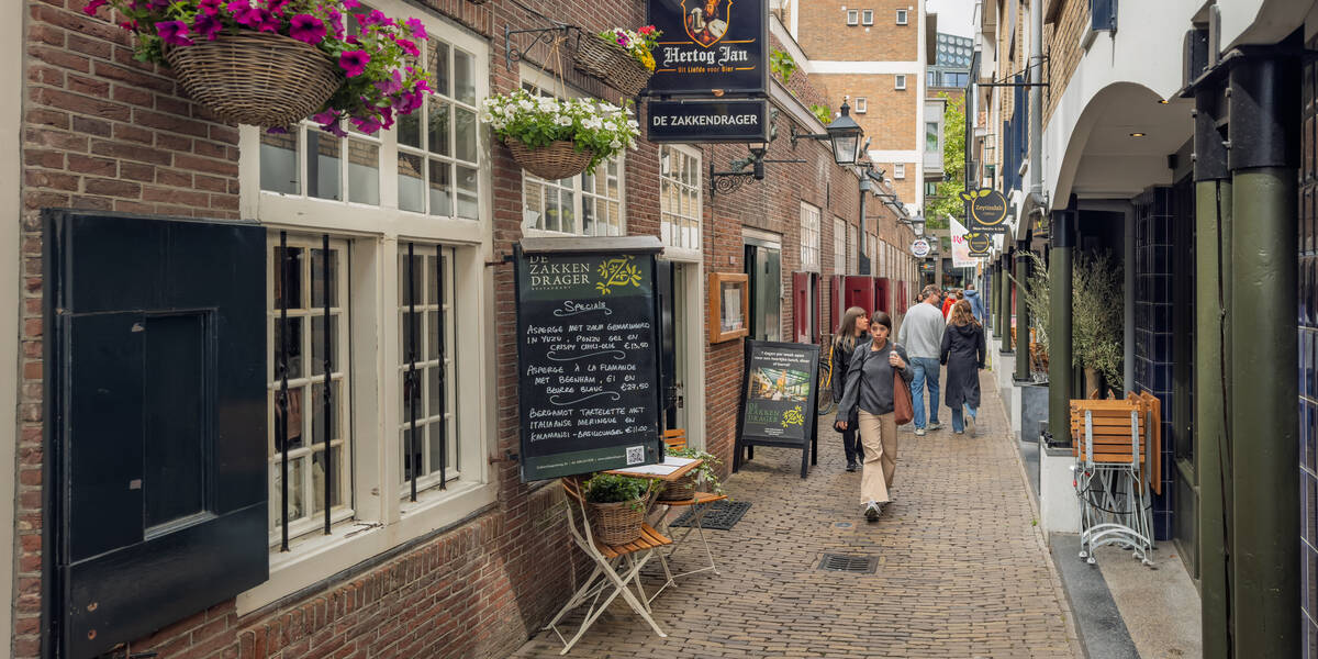 Link naar foto in Flickr: winkelend publiek gaat door de Zakkendragerssteeg.