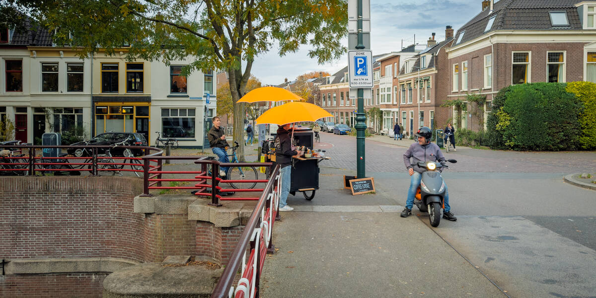 Link naar foto in Flickr: Straatverkoper met klandizie op de Van Asch van Wijcksbrug. Met op de achtergrond Hopakker en Weerdsingel Oostzijde.