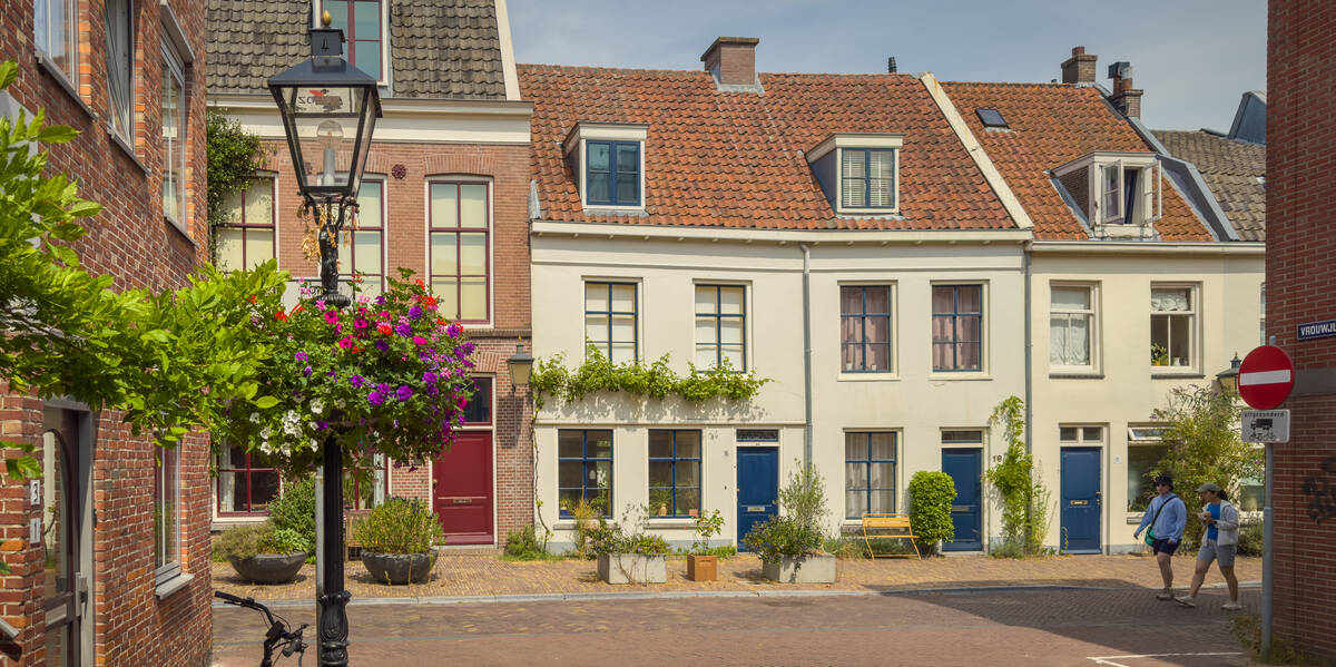 Link naar foto in Flickr: 2 mensen lopen door een zonnige Vrouwjuttenstraat.
