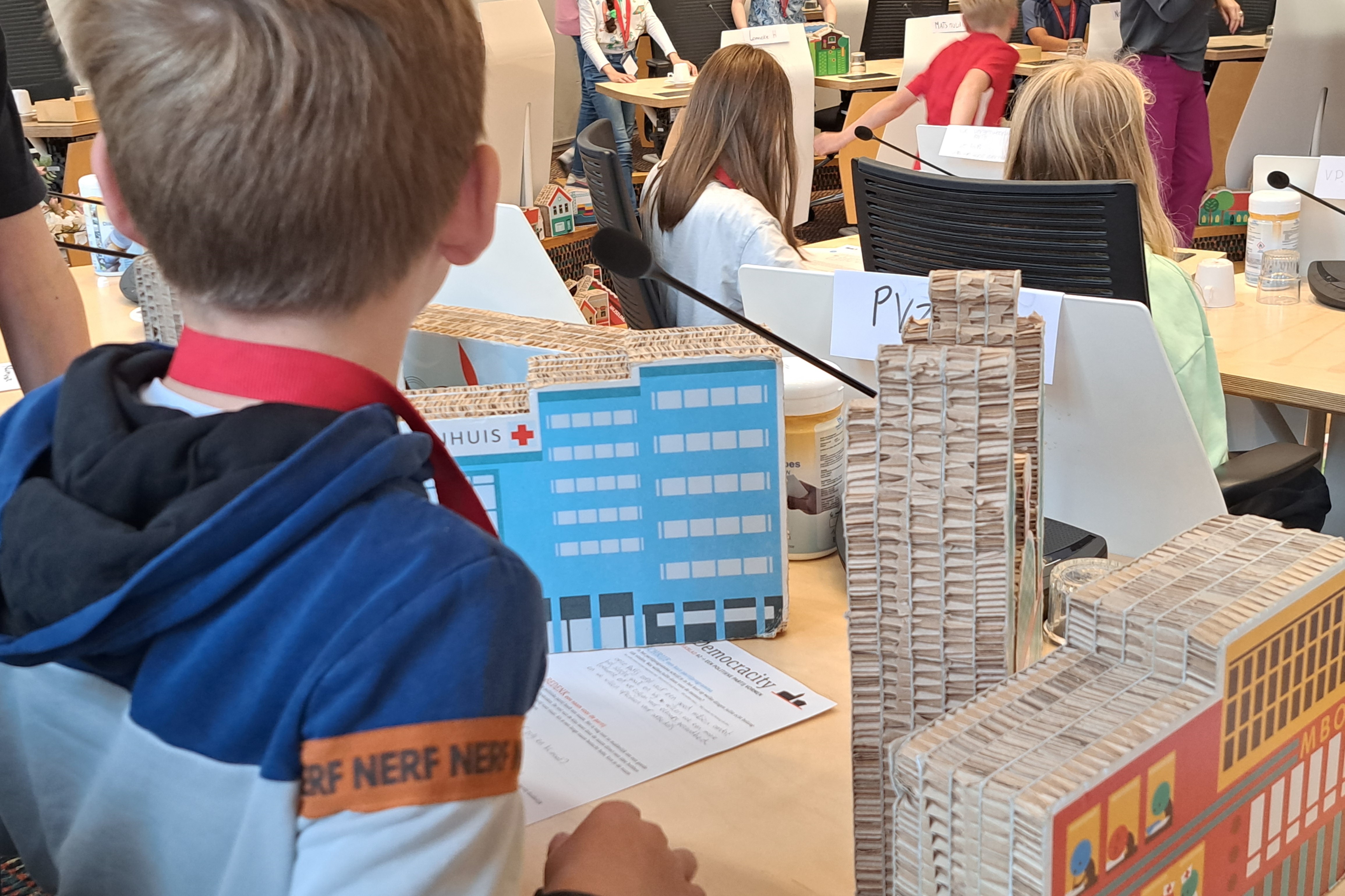 Een basisschoolklas speelt het spel Democracity in de Utrechtse raadszaal. Te zien is een groep kinderen.