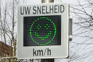 Een snelheidsbord met een groene smiley erop.