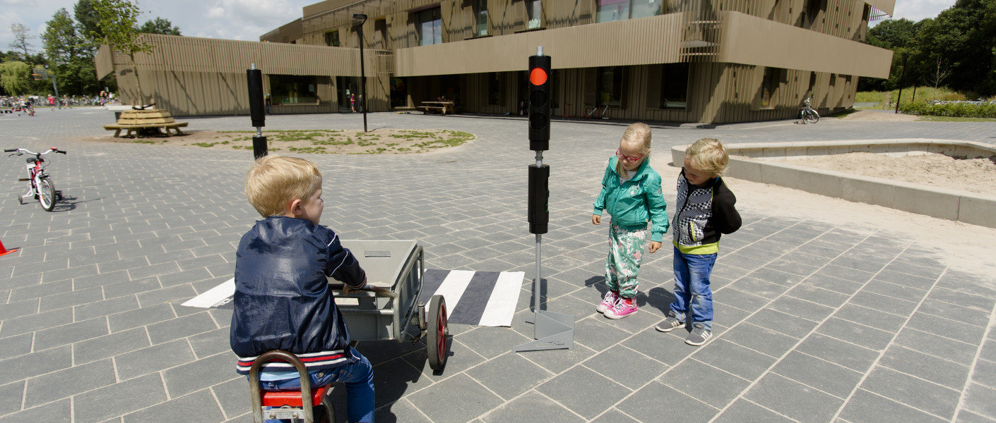 Kleine kinderen oefenen op de fiets met stoplicht en zebrapad
