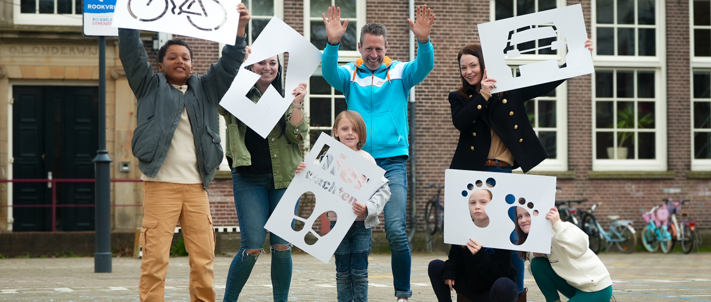 Ouders en kinderen poseren met borden die ze gemaakt hebben voor verkeersveiligheid